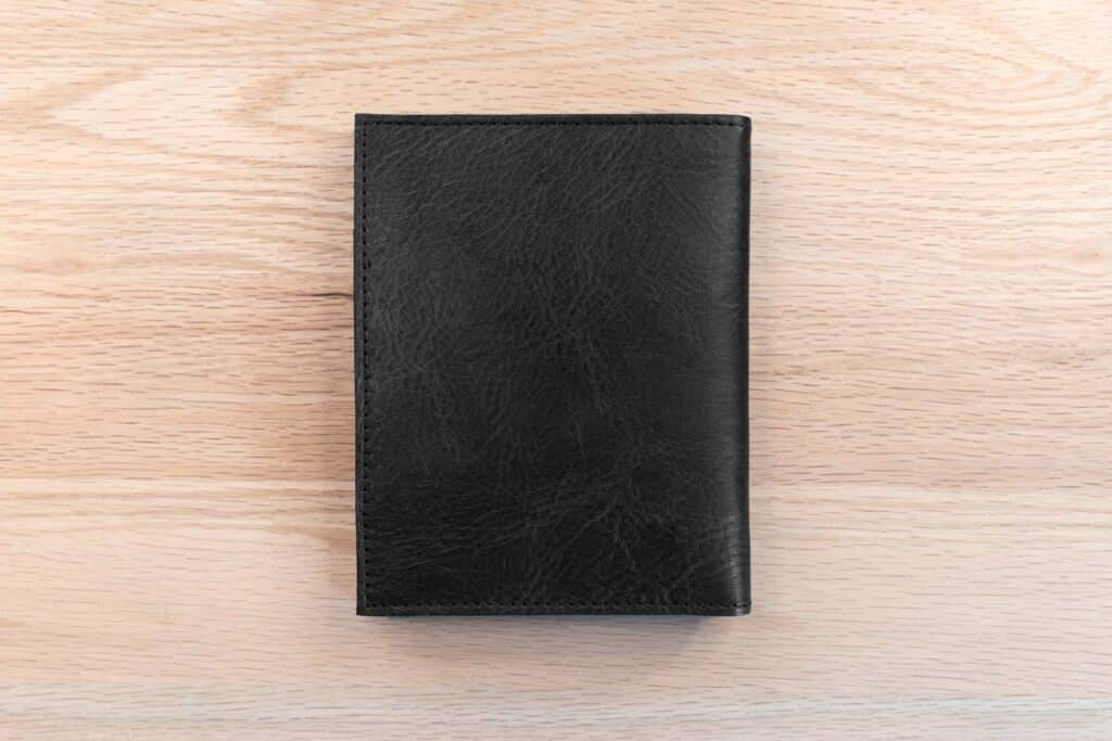 Black Full Grain Leather Passport Wallet Displayed On Oak Wood