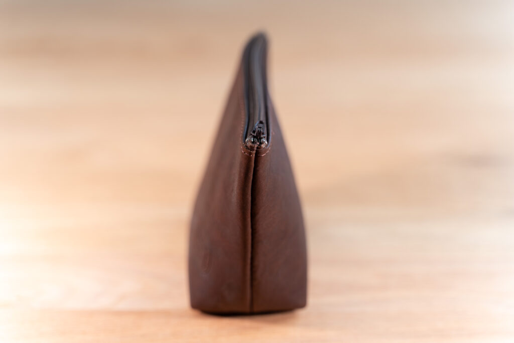 Side View Of The Small Leather Makeup Bag Showing It'S Wider Bottom And Narrow Top