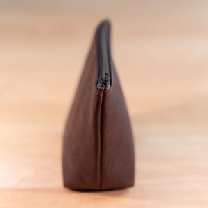 Side view of the small leather makeup bag showing it's wider bottom and narrow top