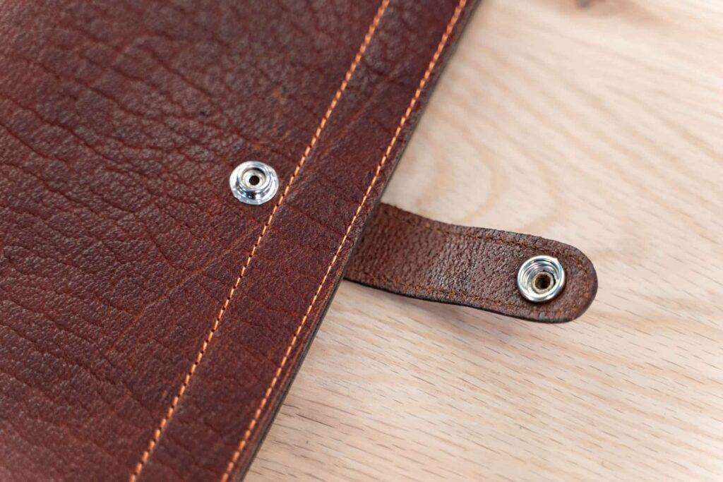 A leather strap with snap closure to keep the 3 ring binder closed