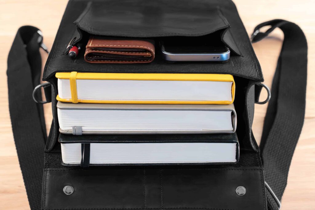 Inside Of Leather Backpack Filled With 3 Thick Books In The Main Compartment, And An Iphone, Wallet, And Pen In The Secured Front Pocket.