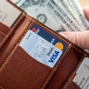 Hand taking money from bill slot in the American Chestnut version of the Mens Leather Trifold Wallet with Vertical Pockets