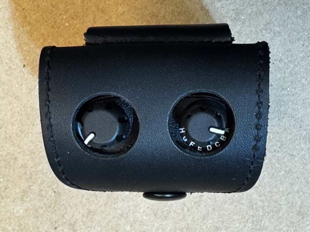Two Dials Of The Motorola Minitor 7 Accessible From The Holes In The Top Of The Black Leather Pager Case. Two Dials Of The Motorola Minitor 7 Accessible From The Holes In The Top Of The Black Leather Pager Case.