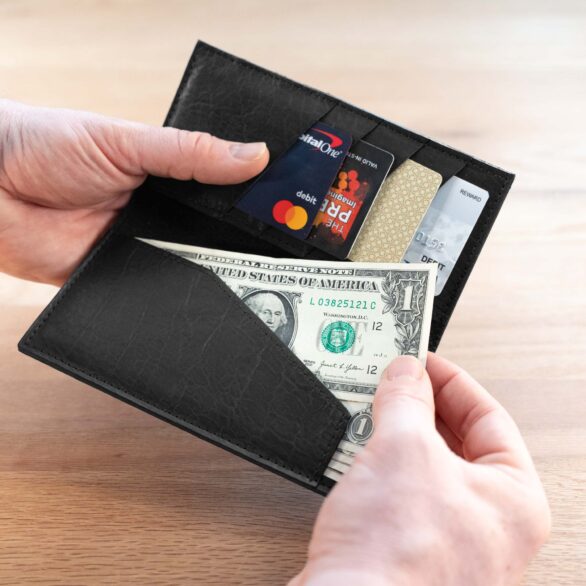 Person taking a dollar bill out of the bill slot on the black leather checkbook wallet.
